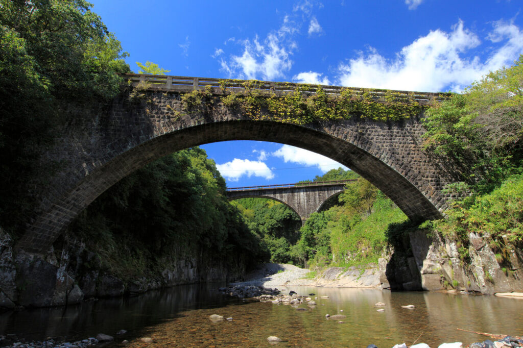 川から見上げた出会橋と、その奥に見える轟橋。青空と雲、豊かな自然に囲まれた歴史ある二つの橋