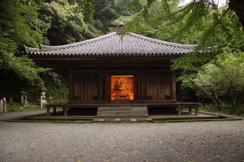 大分県豊後高田市の富貴寺本堂。緑に囲まれた境内、扉が開かれ阿弥陀如来像が橙色の光に包まれて鎮座