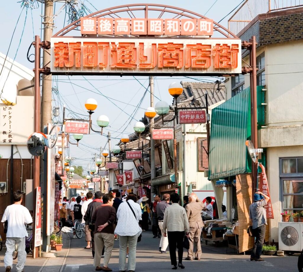 豊後高田昭和の町、新町通り商店街のアーケードを歩く多くの人の後ろ姿