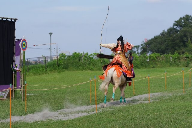 弓を引き絞り的に向かって矢を放つ流鏑馬のイメージ、日本の伝統的な弓術神事