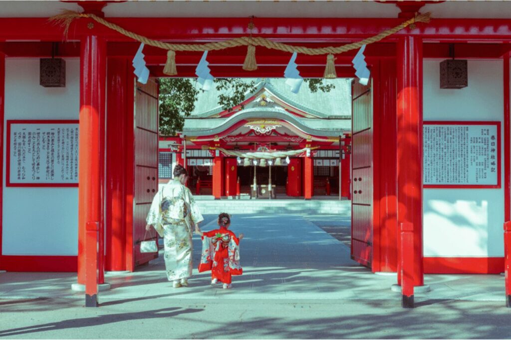 春日神社の鳥居をくぐる着物姿の母と娘(七五三参拝の様子)