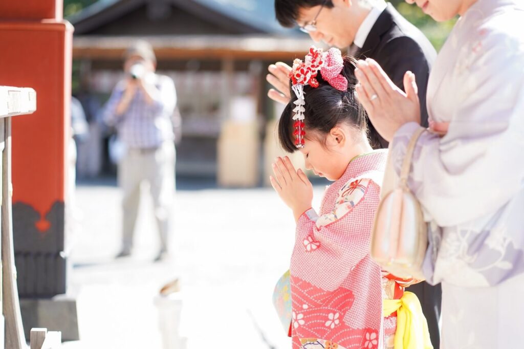 七五三で神社を参拝し、横から手を合わせる親子の姿のイメージ