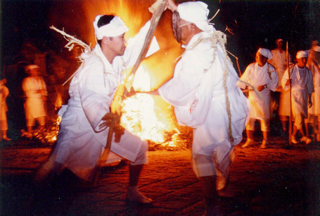 ケベス祭で炎を背に向き合う白装束の二人|櫛来社