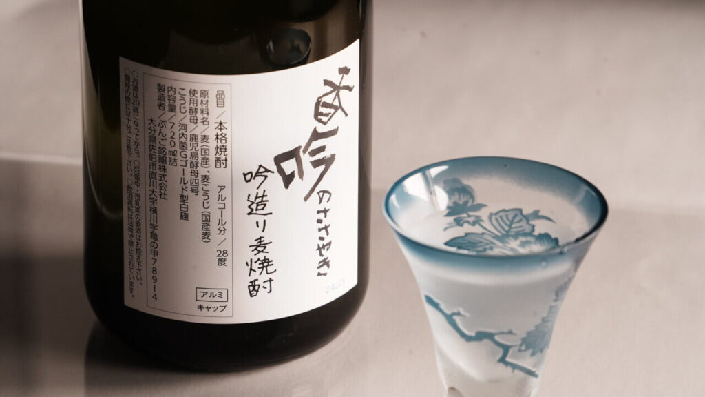 ぶんご銘醸の麦焼酎『香吟のささやき』のラベルとグラスに注がれた焼酎
