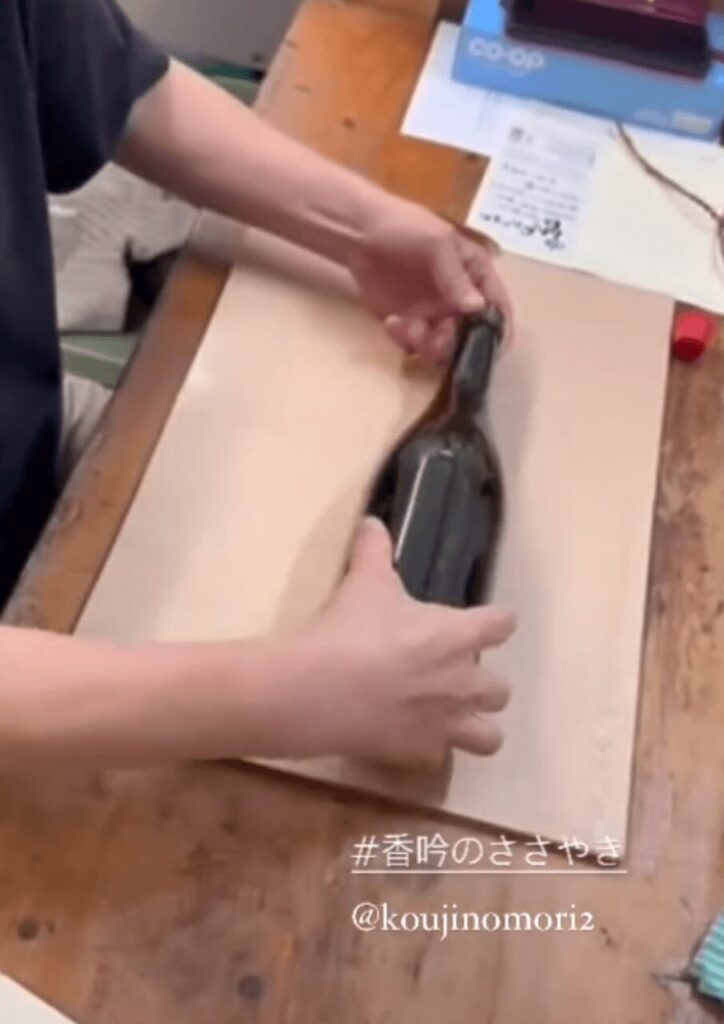 ぶんご銘醸の伝統の手仕事『香吟巻き』で焼酎の瓶を丁寧に包む作業風景