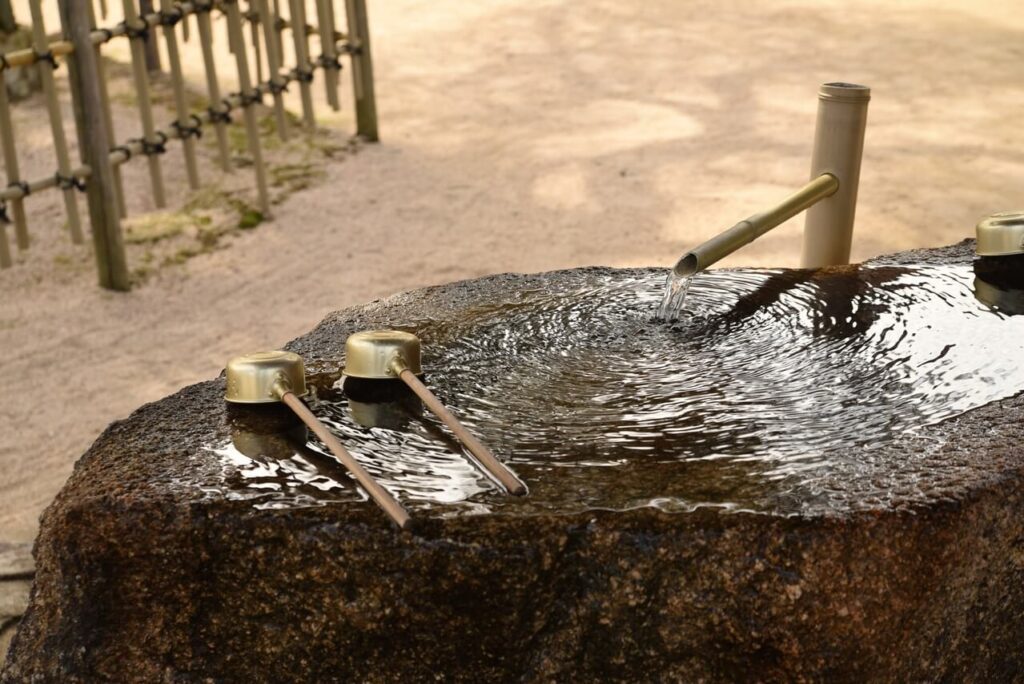 神社の手水場のイメージ、岩に溜めた水と柄杓で手を清める参拝前の風景