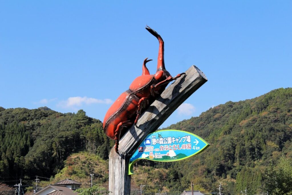かぶとむしの湯まで4kmのカブトムシのオブジェ看板と木にとまる装飾