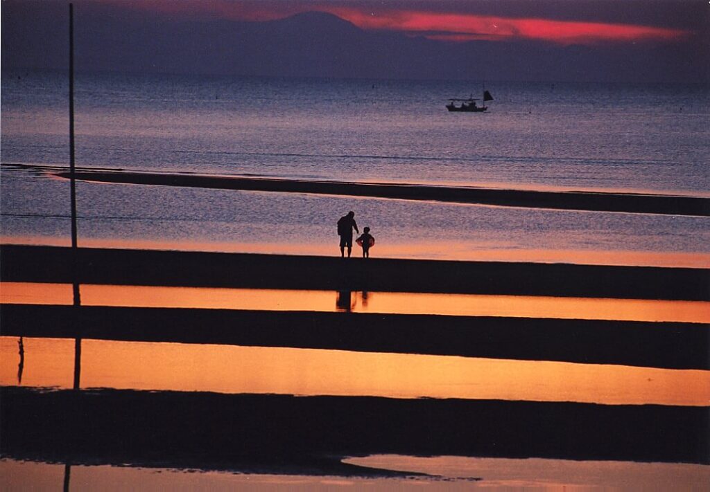 夕方の真玉海岸で家族が干潟を散策する美しい夕景