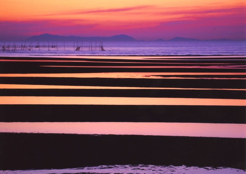 干潮時の真玉海岸で夕日が反射し幻想的に輝く干潟の風景