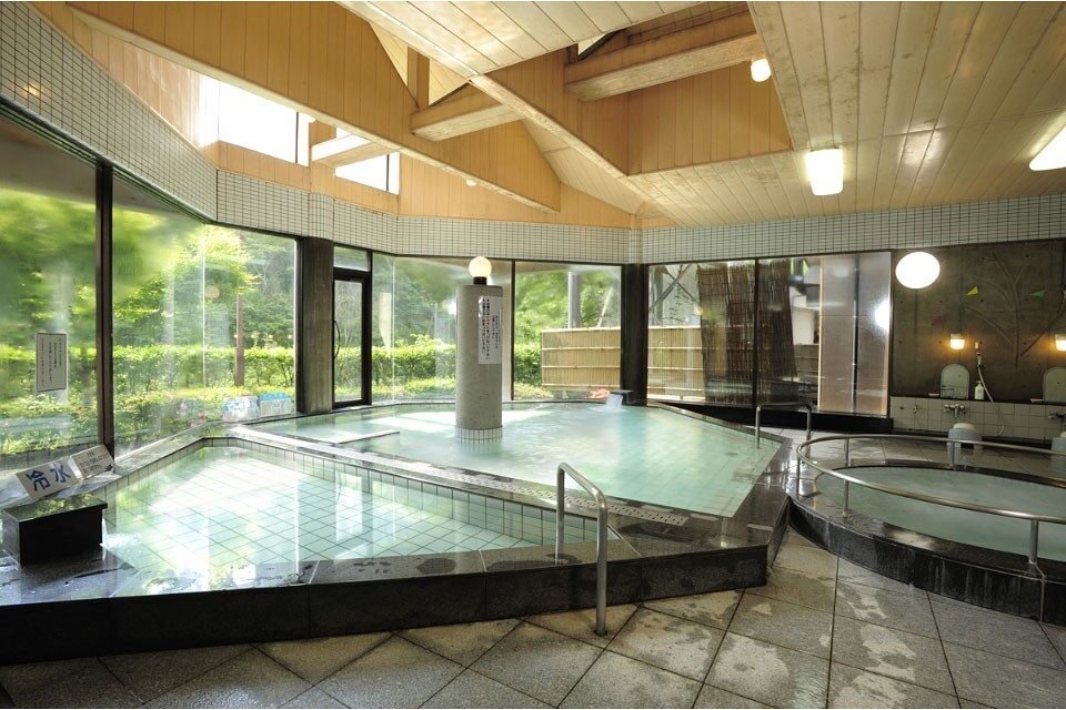 かぶとむしの湯の大浴場。直川特産の直見杉を使った天井と黒大理石の浴槽、左手には冷泉の水風呂