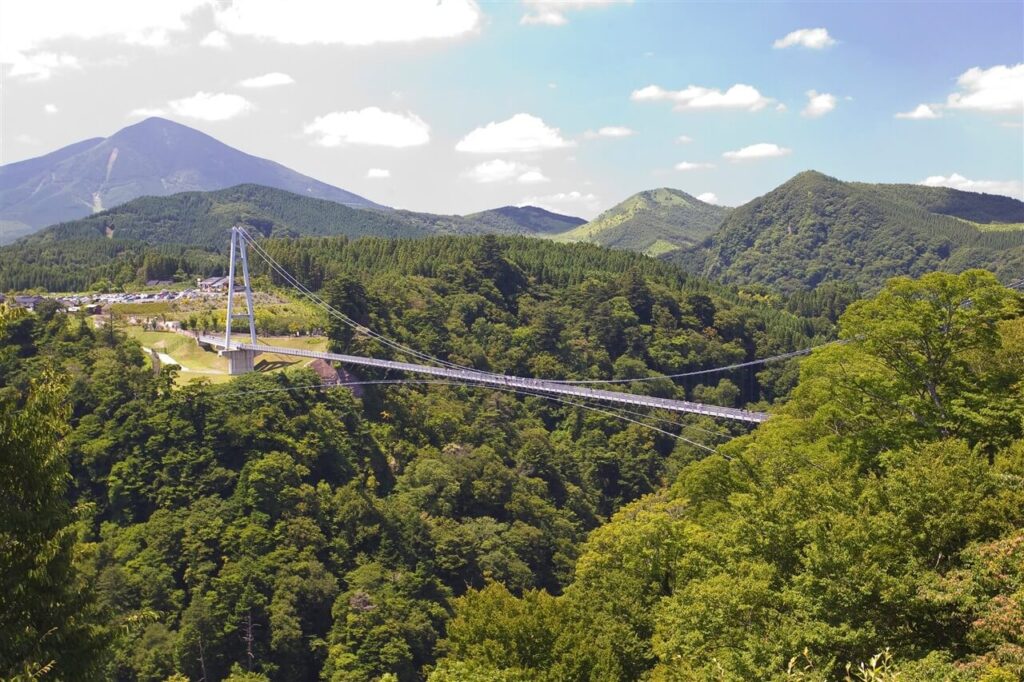 大分観光で一度は訪れたい、春の新緑が美しい豊かな山々の間に架かる九重“夢”大吊橋の遠景