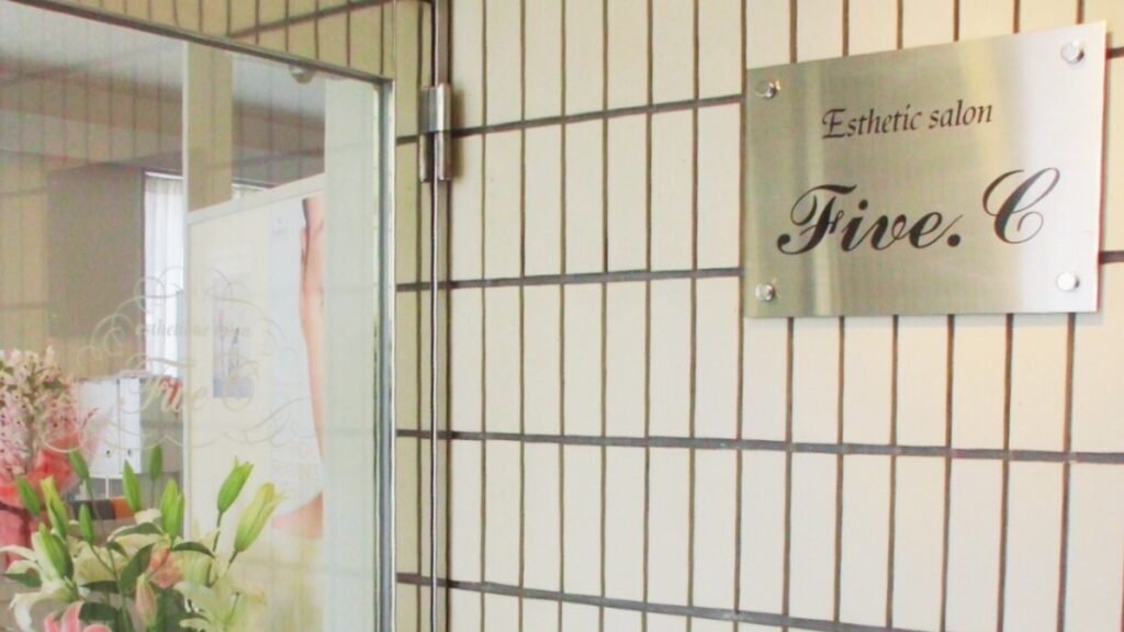 「Esthetic salon Five.C」と刻まれたプレートと、生花が飾られた玄関ドア