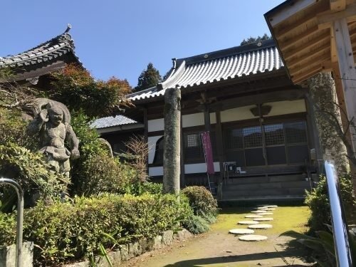 久保山長慶寺の本堂と、参道脇に立つ苔むした仁王石像