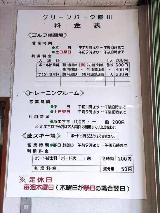 クリーンパーク直川の施設料金案内板。ゴルフ練習場・トレーニングルーム・芝スキー場の営業時間と料金、定休日（毎週木曜）が記されている