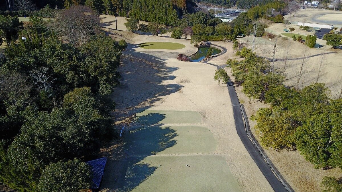 ドローン空撮による直川カントリー倶楽部のコース全景。緑のフェアウェイとバンカー、カート道路が木々に囲まれて広がる